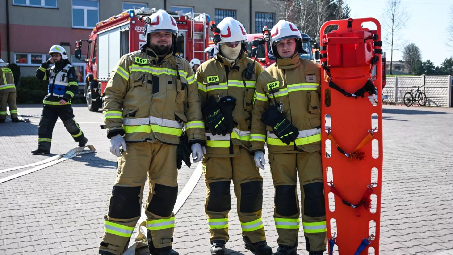 Strażacy z OSP Zbrojewsko na tle samochodów strażackich